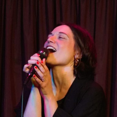 Donna canta con passione, tenendo un microfono, illuminata da luci soffuse.