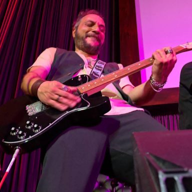 Music performer passionately playing an electric guitar on stage.